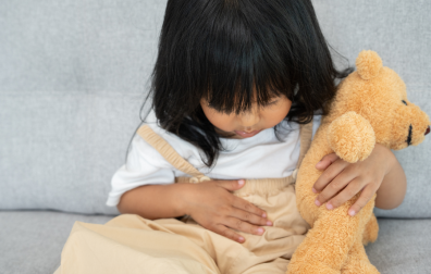 Kind met knuffel houdt haar buik vast