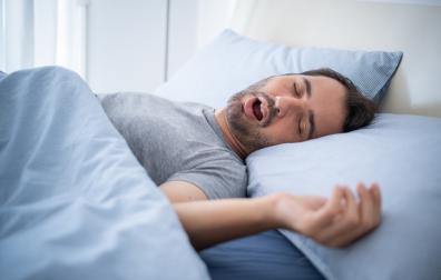 Slapende en snurkende man in bed