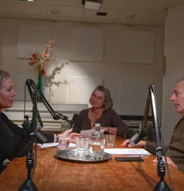 Sprekers van de podcast zitten aan tafel