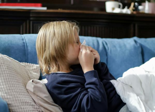 Kind zit op bank en snuit neus