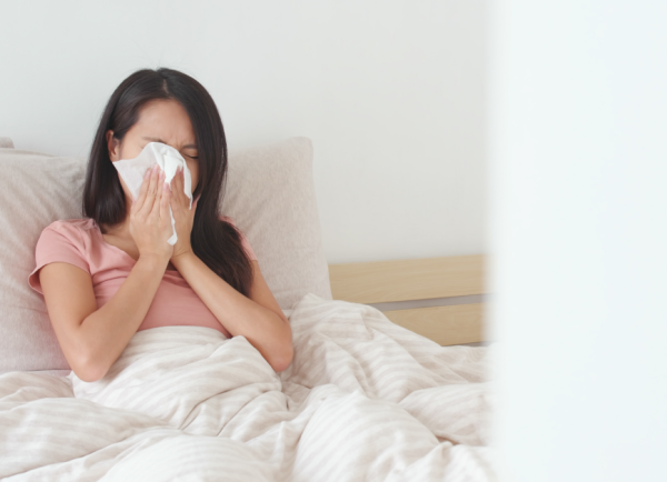 Vrouw ligt in bed en snuit neus